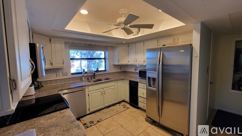 A kitchen with white cabinets and a stainless steel refrigerator.