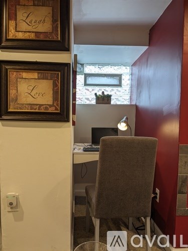 A room with a desk, chair, and two framed words "Laugh Love" on the wall.
