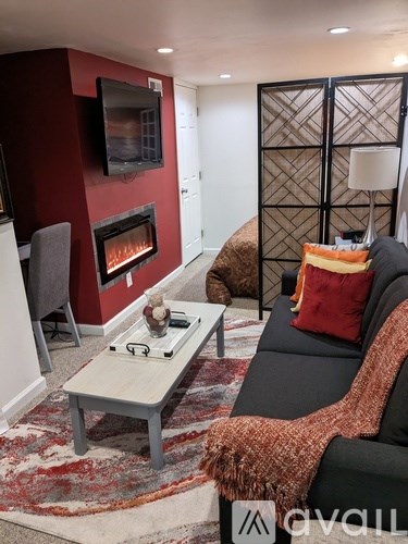 A living room with a black couch and a fireplace.