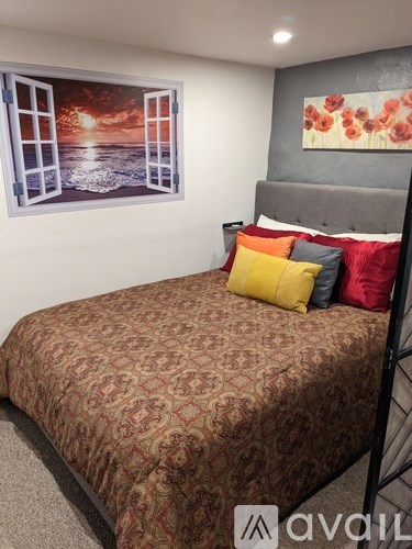 A bed with a patterned cover and a picture of an ocean scene on the wall.