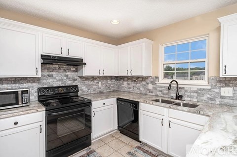 A kitchen with white cabinets and a black stove top oven.