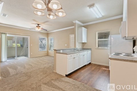 A kitchen with a refrigerator, stove, and a ceiling fan.