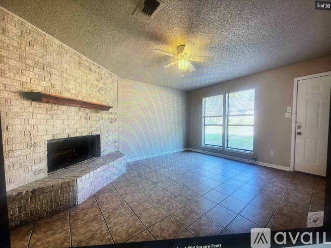 A living room with a fireplace and a ceiling fan.