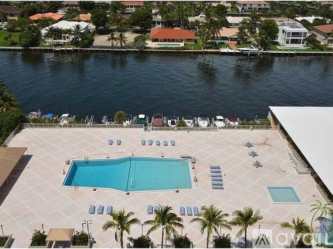 A large swimming pool surrounded by sun loungers and palm trees.