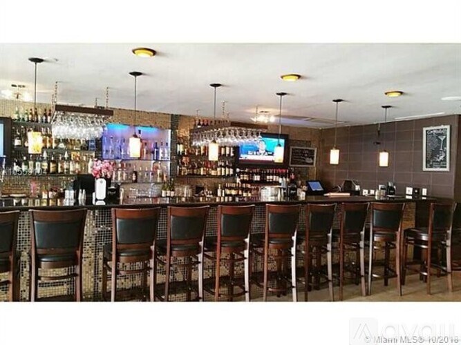 A bar with wooden chairs and a television on the wall.