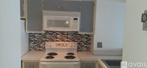 A kitchen with a white stove top oven and a microwave above it.