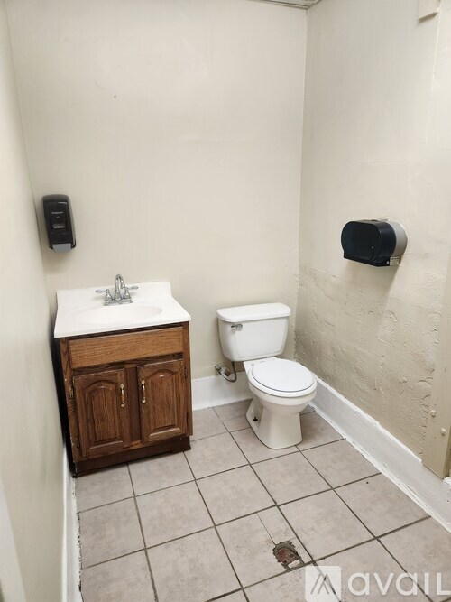 A bathroom with a toilet, sink, and a trash can.