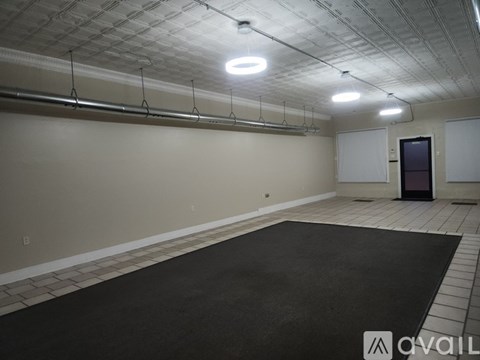 A spacious room with a black carpet and white walls.