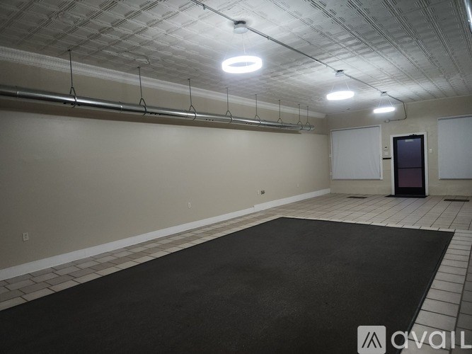 A spacious room with a black carpet and white walls.