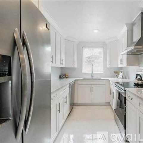 A modern kitchen with white cabinets and stainless steel appliances.