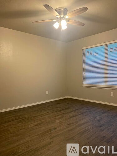 A room with a ceiling fan and wooden flooring.