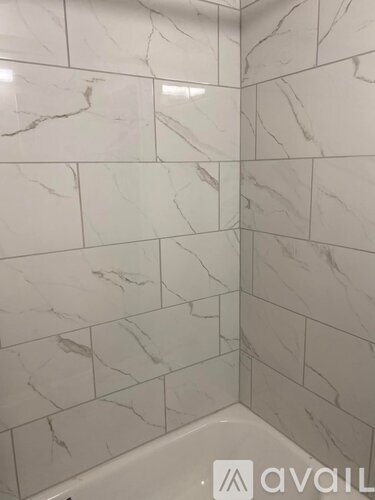 A white tiled bathroom wall with a marble pattern.