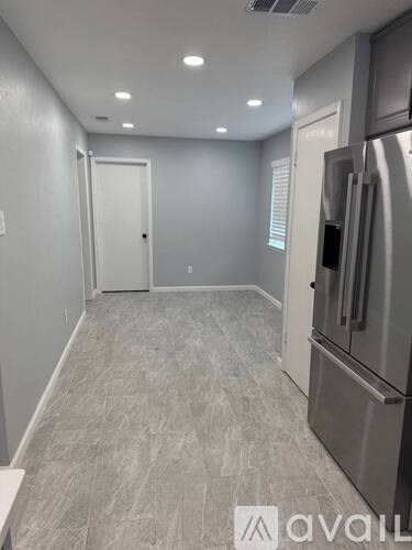 A kitchen with a stainless steel refrigerator and a tiled floor.