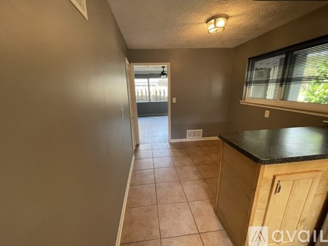 A long hallway with a black counter top and tiled floor.