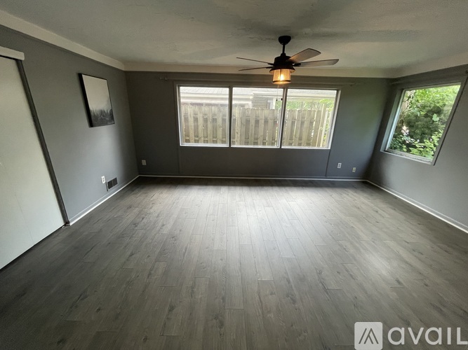 A room with a ceiling fan and wooden flooring.