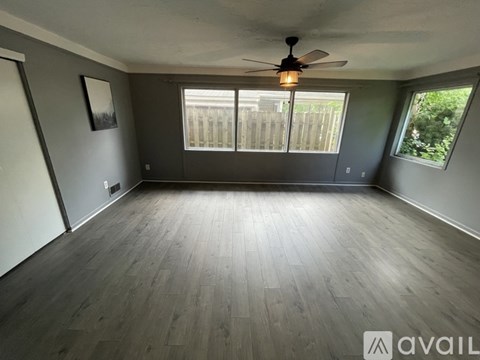 A room with a ceiling fan and wooden flooring.