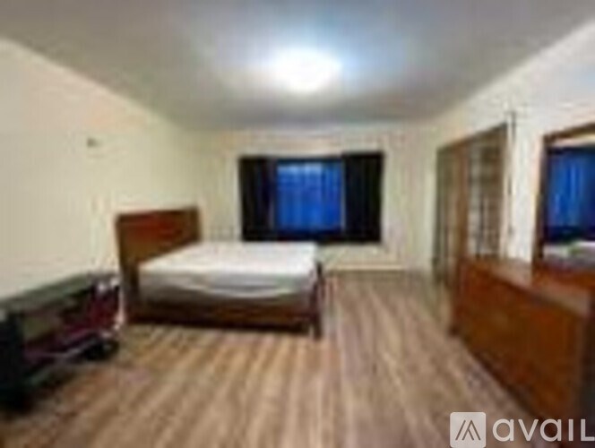 A bedroom with a bed, dresser, and window.