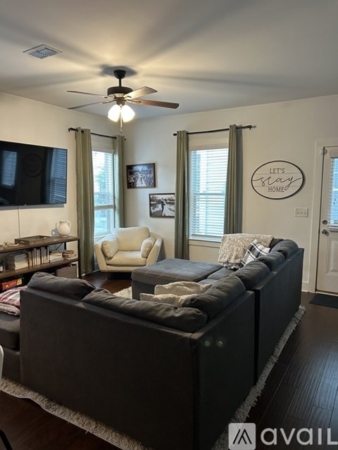 A living room with a grey couch and a fan on the ceiling.