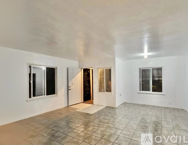 A spacious room with tile flooring and white walls.