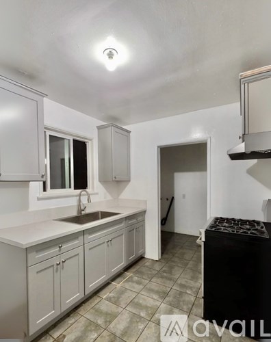 A kitchen with white cabinets and a black fridge.