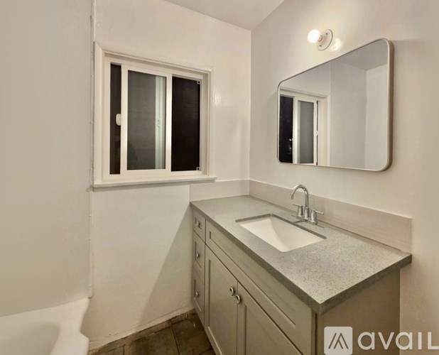 A bathroom with a sink, mirror, and a window.