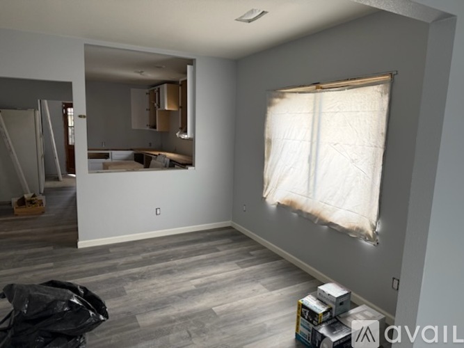 A room with a window covered in a white cloth and a black bag on the floor.