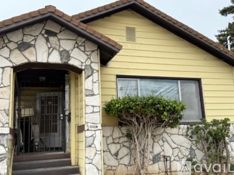 A house with a stone archway entrance and a window with a tree growing out of it.