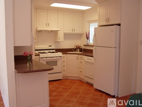 A kitchen with white cabinets and a white refrigerator.
