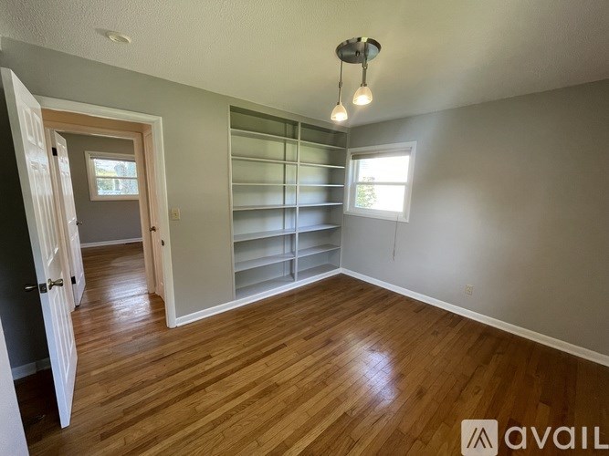 A bathroom with a white door, a sink, a mirror, and a toilet.