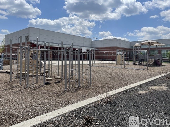 A playground with a slide and a building in the background.