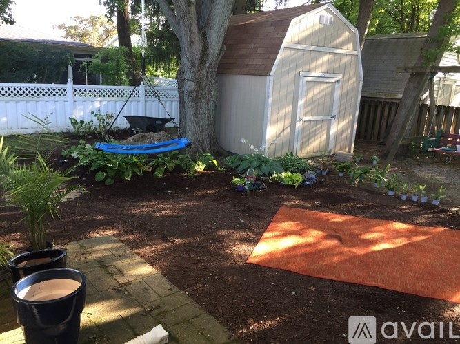 A backyard with a shed, a tree, and a small garden.