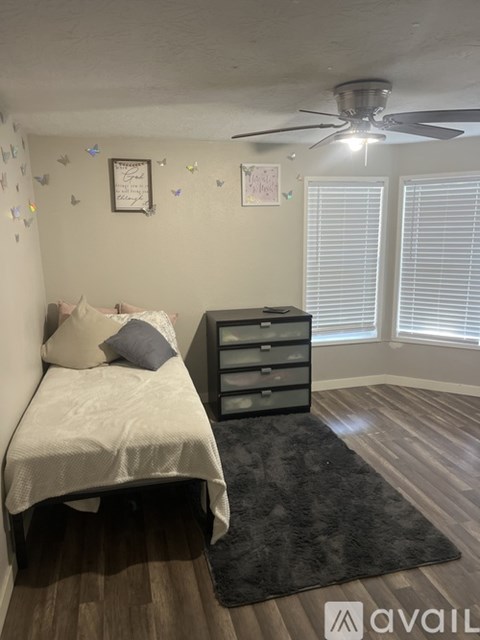 A bedroom with a bed, dresser, and ceiling fan.