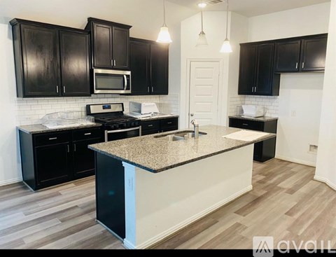 A kitchen with black cabinets and a granite countertop.
