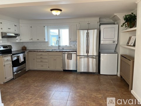 A kitchen with white cabinets and a tiled floor.