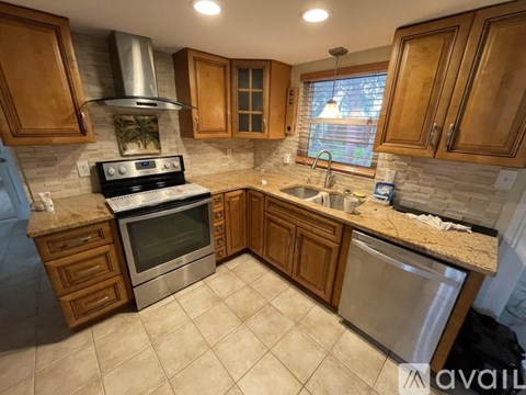 A kitchen with wooden cabinets and a stainless steel dishwasher.