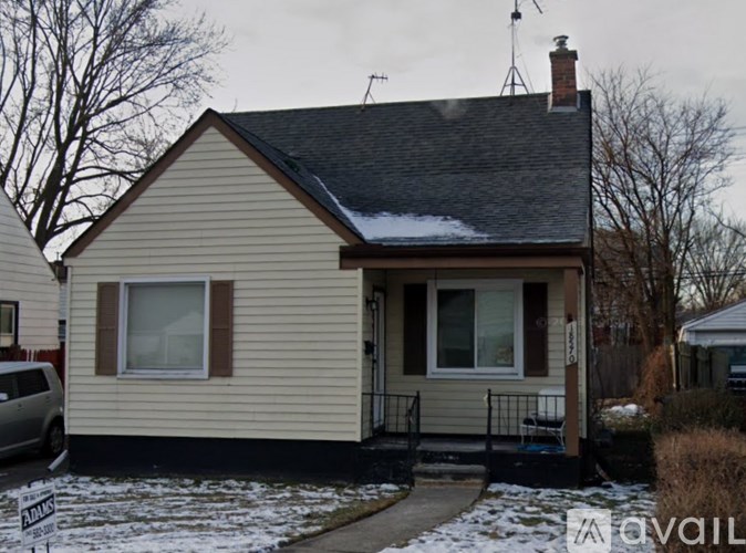 A small house with a brown roof and a white wall with a window and a door.