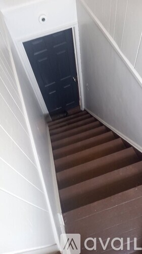 A stairway with a black door at the bottom.