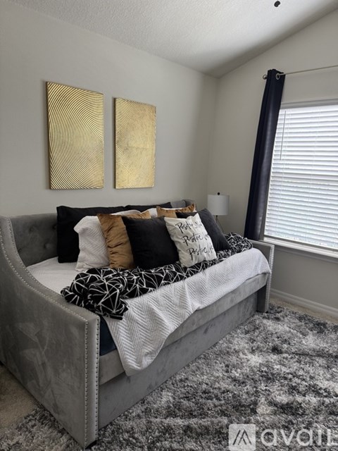 A bedroom with a grey bed and a grey rug.