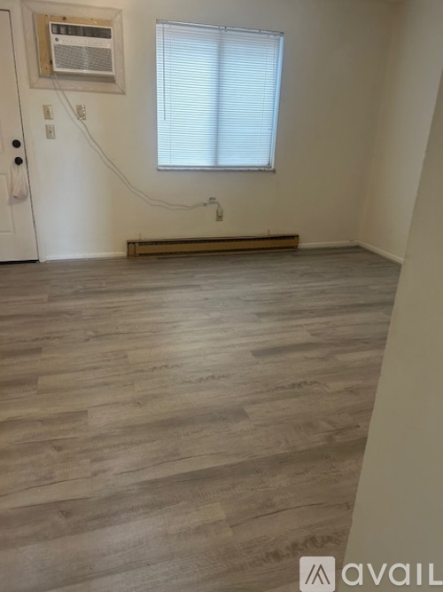 A room with a window and a wooden floor.