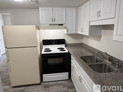 A kitchen with a white fridge, stove, and cabinets.
