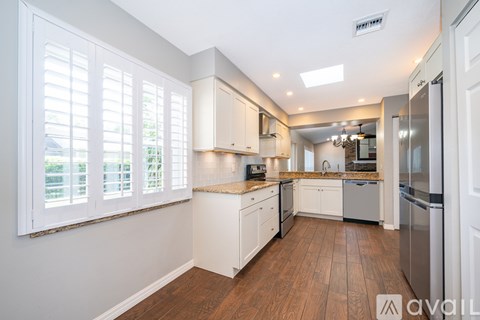 A kitchen with white cabinets and a wooden floor.