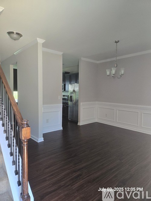 A living room with wood floors and a staircase with a wooden railing.