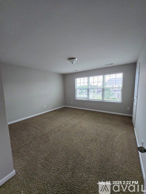 A room with carpeted floor and a window showing a view of a building.