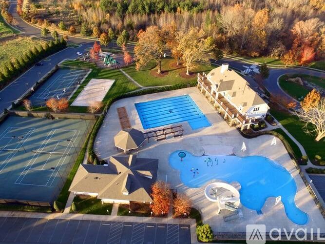 An aerial view of a swimming pool surrounded by trees and a building.