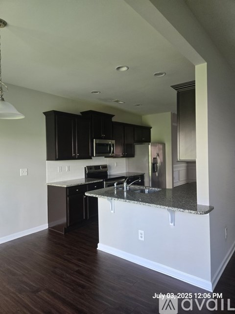 A kitchen with dark brown cabinets and a granite countertop.