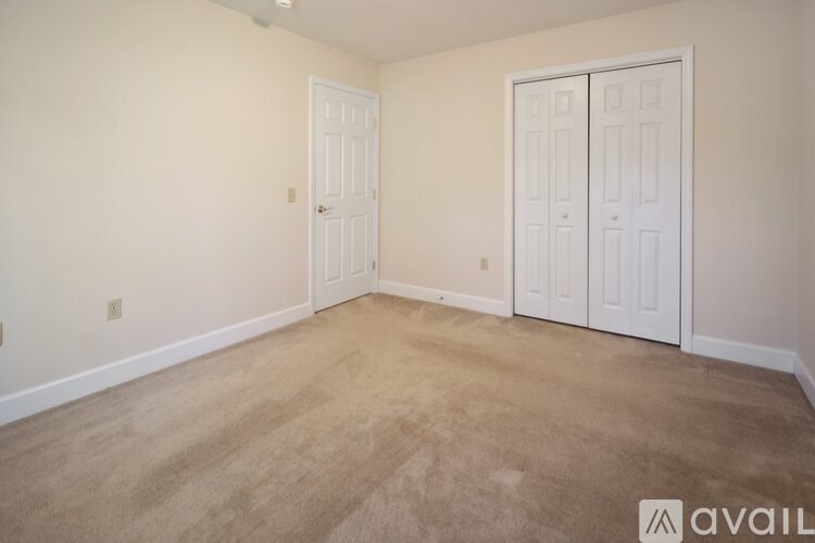 A room with a carpeted floor and two doors.