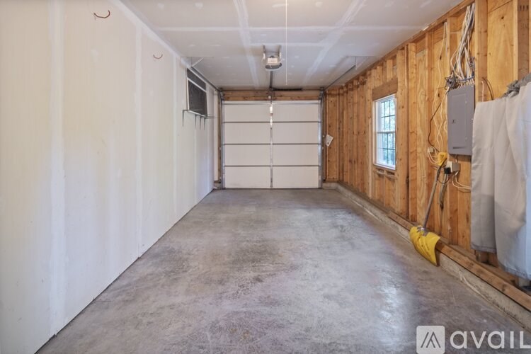 A large empty room with a garage door and wooden walls.