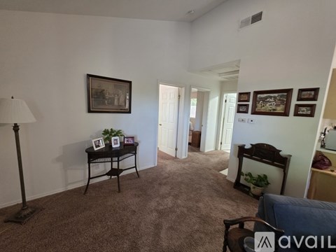 A living room with a lamp, a table with a plant and a picture frame, and a couch.