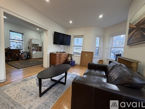 A living room with a brown couch, a coffee table, and a ceiling fan.