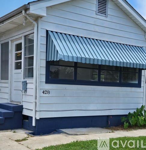 A white house with a blue awning and the number 428 on it.